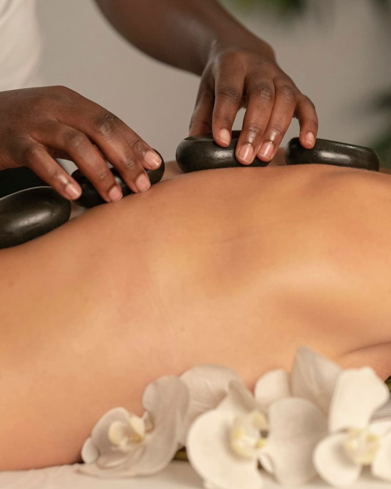 Smooth massage stones resting on folded natural linen beside a candle